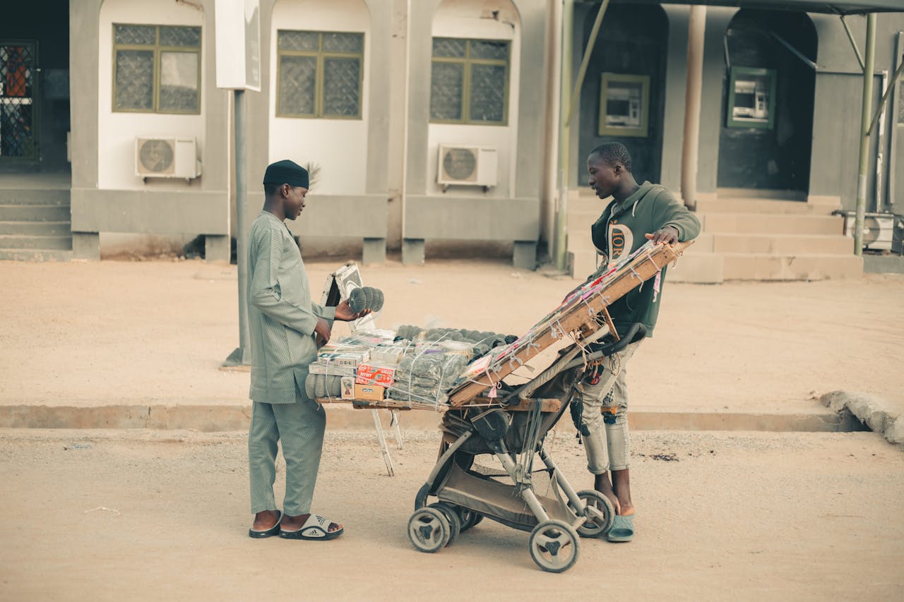 Urban street scene showing a vendor selling traditional goods to a customer.